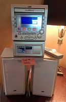 Front view of JVC stereo stacked on speakers showing controls, display and cassette deck