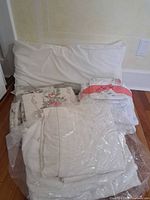 Pile of white sheets, floral bedding pieces and two standard pillows