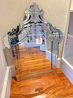 Full view of Venetian style mirrored floor mirror leaning against wall