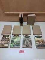 All 11 books laid out: 7 leatherette hardcovers and 4 paperbacks visible