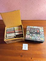 Overall view showing cardboard box of loose cassette tapes beside boxed set
