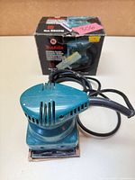 Front view of Makita B04510 sander with power cord, box in background