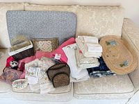 All items spread on sofa including towels, linens, blanket, hat, basket, pillow, pouches