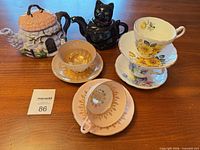 Front view showing both novelty teapots and four teacup/saucer sets