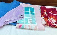 All six towels displayed: two blue, red floral with washcloth, pink graphic beach towel, purple hair towel