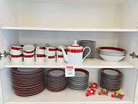 Full set on shelving showing cups, teapot, plates, bowls, napkin rings