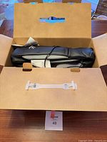 Massager inside original cardboard box with adapter visible