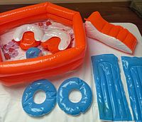 Overall set showing pool, curved cushions, blue ring floats, lounge mats, and orange-white seat