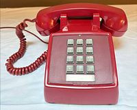 Front view showing full telephone with handset, coiled cord, and keypad