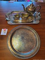 Full view: teapot, creamer, sugar bowl on rectangular tray, round platter in foreground