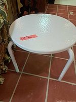 Top view of white metal round side table showing textured surface and three legs