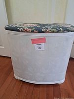 Front view of white plastic storage bench with floral padded top