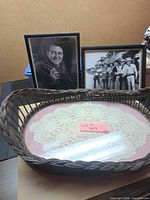 Overall lot showing wicker tray, two framed photos, doily