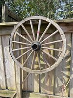 Front view of complete wooden wagon wheel against fence