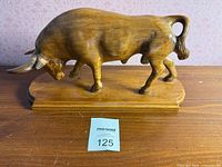 Full view of wooden bull figurine on base showing finish and form