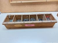 Top view of wooden organizer showing six compartments filled with nails, jar visible.