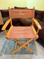 Front view of folding wooden director's chair showing canvas seat and embroidered back
