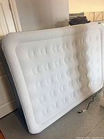 Light gray double-height queen air mattress leaning against wall