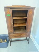 Full frontal view of cabinet showing door, shelves, drawer and legs