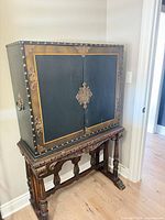 Front view of cabinet closed on carved stand showing overall design and hardware