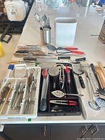 Full layout of utensils on countertop and in open drawer showing quantity and variety