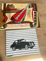 Both paintings front view: abstract musical instruments canvas above, vintage car canvas below