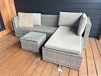 Full view of gray wicker sectional with chaise and square table on deck