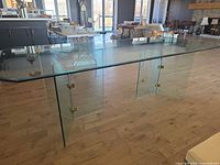 Full side view of glass dining table showing top, bases, brass hardware