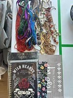 Overview of necklaces, notebooks and painted sign on table