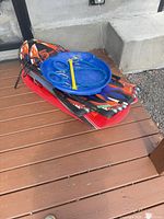 Stack showing red toboggan, two foam boards, blue saucer on deck