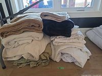 Stack of assorted blankets, sheets, comforter and protector