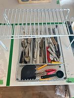 Top view of shelf riser over mesh tray filled with flatware and utensils