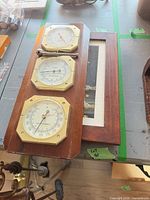 Triple instrument wood plaque with brass bezels next to framed knot art