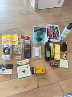 Wide view of assorted items including mouse, pens, ink, push pins, calculator, staples, telephone, sticky notes