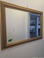Front view of large rectangular gold gilt framed mirror on wall