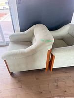 Side view of both armchairs showing upholstery color and wood legs