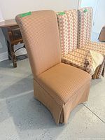 Front view of a plaid slipcovered Parsons chair with another geometric patterned chair beside it
