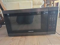 Front view of Samsung black countertop microwave with glass door and control panel