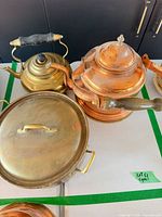 Group shot of copper kettle, brass kettle, brass lidded pan