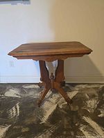 Full view of antique side table showing carved base and casters