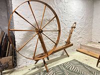 Full view of the wooden spinning wheel on bench base