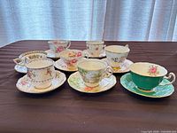 Group of eight teacup and saucer pairs on table