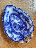 Top view of leaf-shaped flow blue serving tray showing pattern, handle and gilt accents