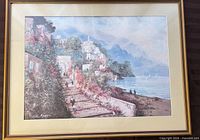 Full view of framed coastal seascape print in gold frame with cream mat