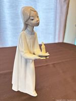 Front view of figurine standing holding candle