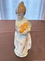 Front view of figurine showing girl holding oranges, color details