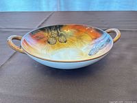 Side view of shallow porcelain bowl showing hand-painted interior and both loop handles