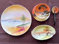 Top view of four hand-painted porcelain pieces: plate, bowl, serving dish, spoon