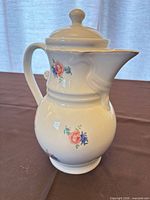 Right-side view of porcelain pitcher showing floral decals, lid and gilded trim