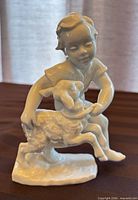 Front view of glossy porcelain figurine boy with lamb